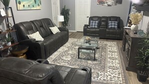 A living room with leather sofas, a glass coffee table, and a patterned rug.