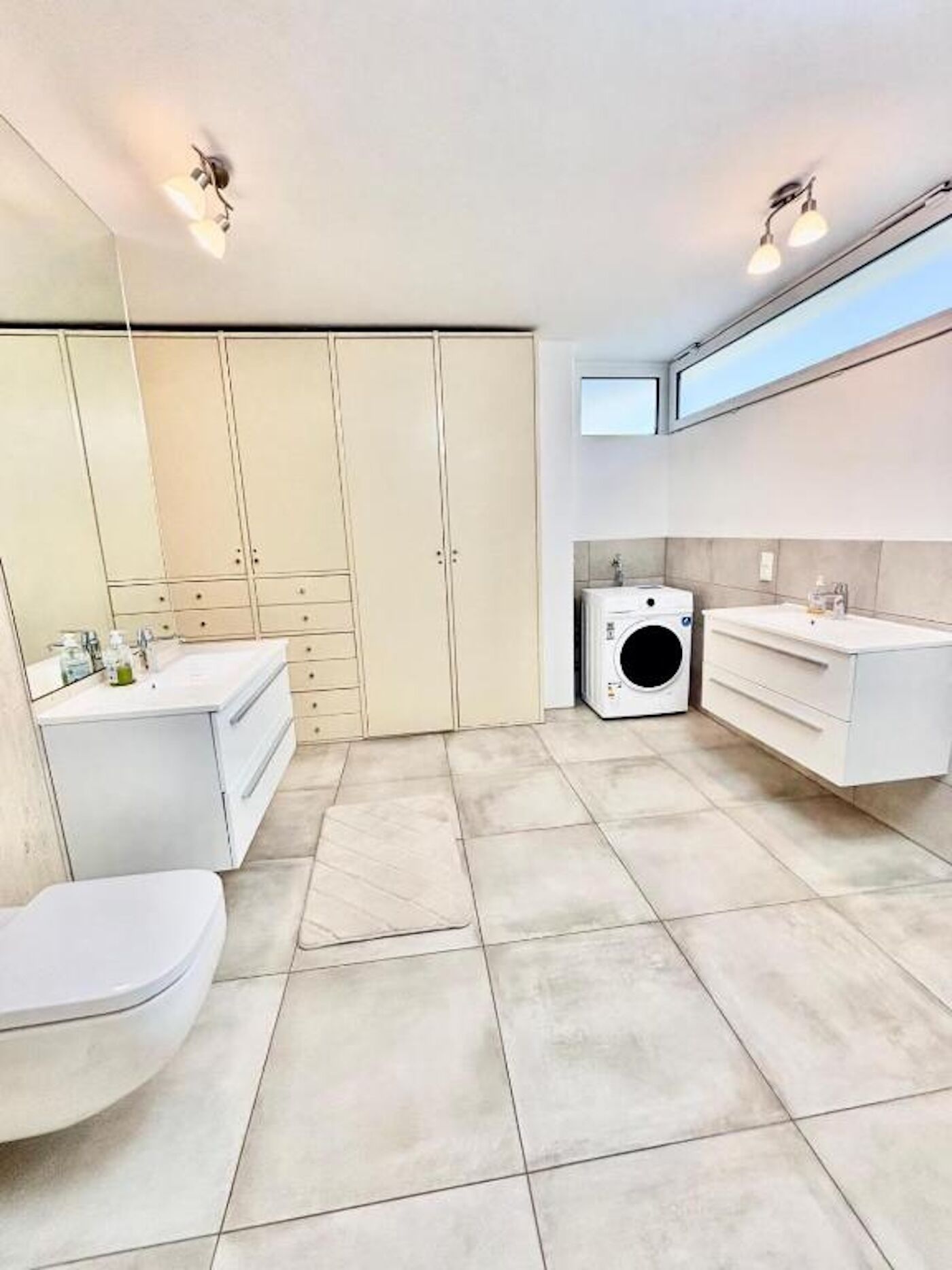 Un baño moderno con inodoro, lavabo y lavadora.