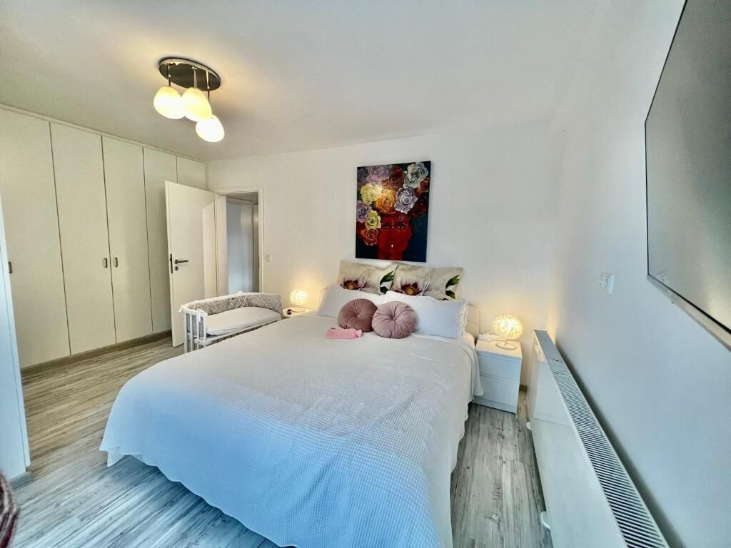 A bedroom with a bed, bedside tables, a painting, and a wardrobe.