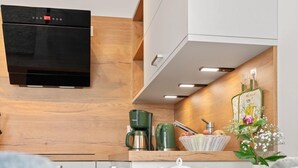 A compact kitchenette with a microwave, coffee maker, and a small dining area with a table set for two. - Ostseeliebe Wg. 6 /1. Etage - Neue, Hochwertig Eingerichtete Wohnung in Strandnähe (Zingst)