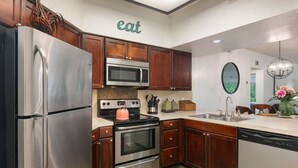 A kitchen with stainless steel appliances, wooden cabinets, a microwave, an oven, and a dishwasher.