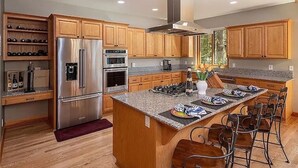 Une cuisine moderne avec des meubles en bois, des appareils électroménagers en acier inoxydable et un îlot central doté de tabourets de bar.