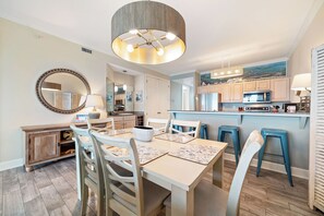 Una cocina moderna con una isla central, armarios blancos y una zona de comedor con mesa y sillas.