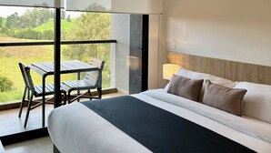 A modern bedroom with a large bed, a small table, and a chair. - Hotel rioverde (Rionegro)