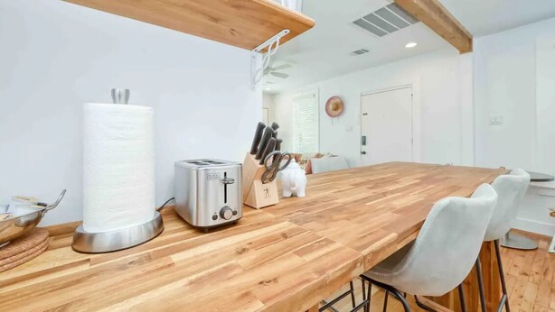 Een keuken met een houten aanrecht, een broodrooster, een papieren handdoekdispenser en een messenblok.
