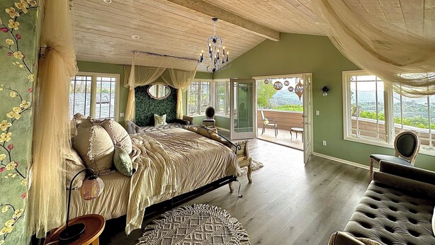A spacious bedroom with a large bed, a chandelier, and a view of the outdoors. - Luxury vacation home, beautiful decor and views! natures 20 acre villa (Escondido)
