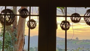 A room with a large window overlooking a landscape, featuring a tree and hanging wicker baskets. - Luxury vacation home, beautiful decor and views! natures 20 acre villa (Escondido)