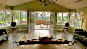 A spacious room with a large bed, a chandelier, and a view of a balcony with outdoor furniture. - Luxury vacation home, beautiful decor and views! natures 20 acre villa (Escondido)