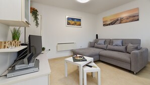 A modern living room with a grey sofa, a white coffee table, and a flat-screen TV on a white stand. - Apartment 2333/111878 (Istria - Pula), 3000m from the beach (Pula)