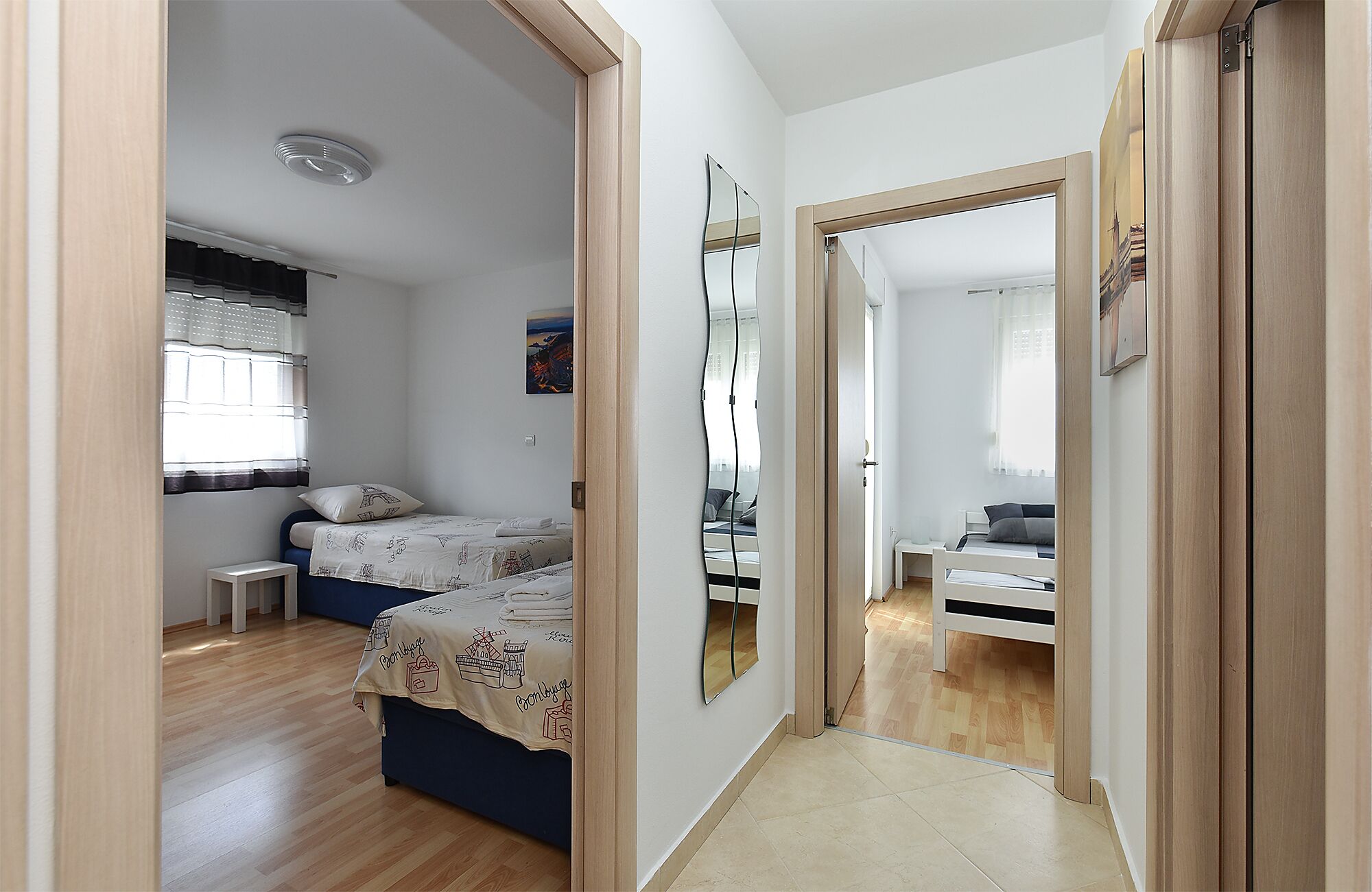 A narrow hallway with a bed on the left and a door leading to another room on the right.