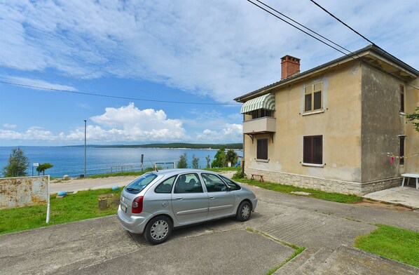 A silver car parked in front of a building with a view of the sea.