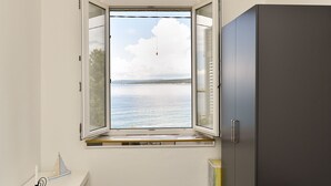 Una habitación con ventana que da a una masa de agua, un estante pequeño y un armario.