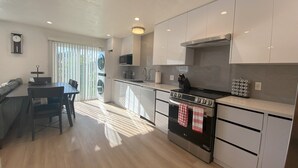Una cocina moderna con armarios blancos, una estufa negra y una zona de comedor con mesa y sillas.