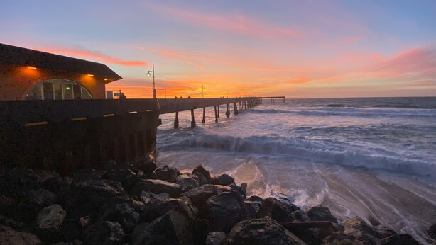 Un muelle que se adentra en el océano, con un edificio a la izquierda.