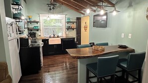 Une cuisine avec un îlot central en bois, un parquet en bois foncé et une fenêtre équipée de stores.