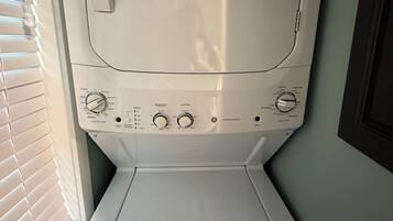 Un appareil combiné lave-linge et sèche-linge à chargement frontal, doté de boutons de commande, d’un bouton de démarrage et d’une étiquette indiquant qu’il s’agit d’un appareil de la marque GE.