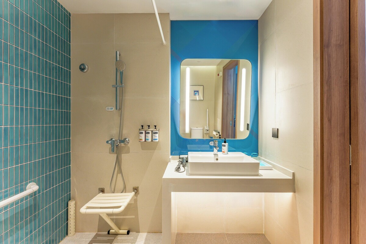 A bathroom with a shower, a sink, and a mirror.