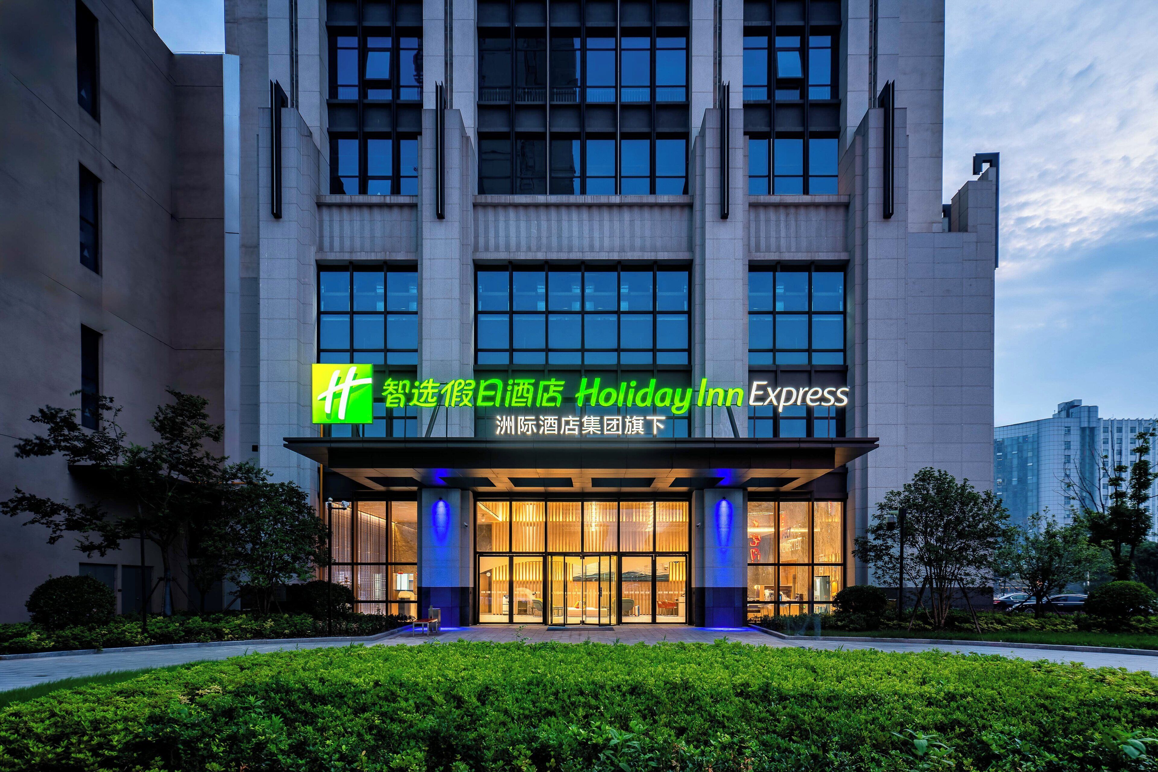A Holiday Inn Express building with a modern facade, large windows, and a well-lit entrance.