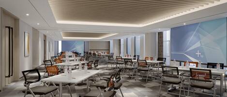 A modern conference room with multiple tables and chairs, large windows, and a geometric wall design.