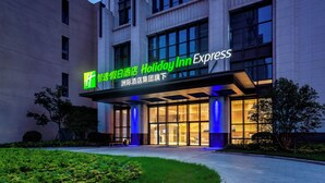 Ingresso di un hotel Holiday Inn Express dal design moderno, caratterizzato da ampie vetrate e una facciata ben illuminata.