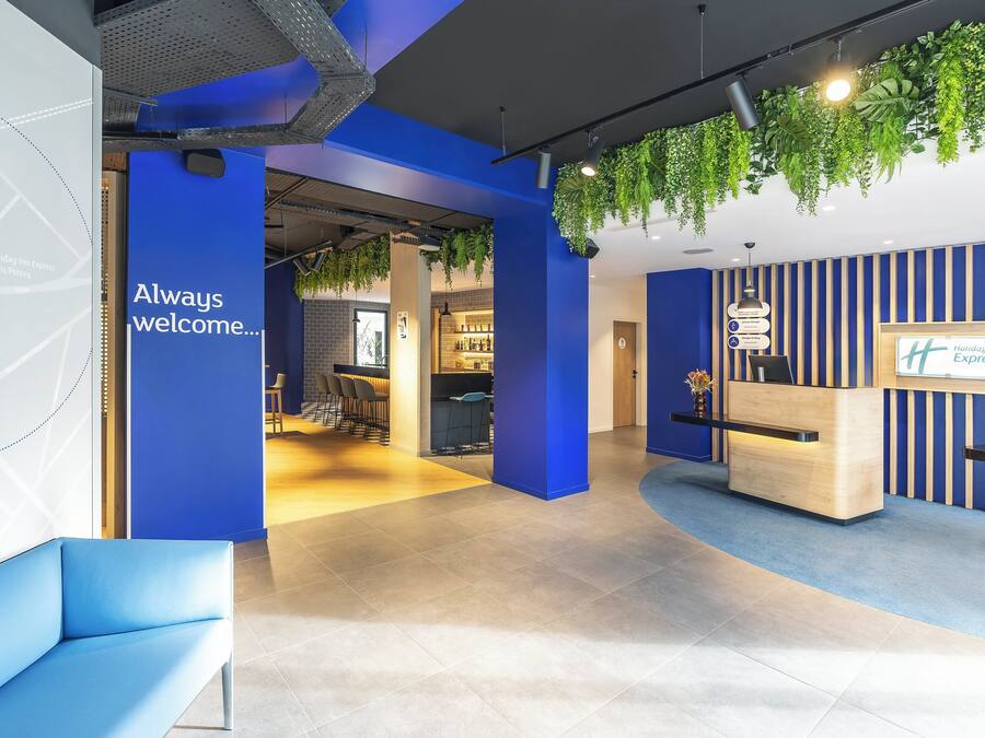 Zona d'arribada moderna amb una combinació de colors blau i blanc, un taulell de recepció i una zona d'espera amb un sofà blau.