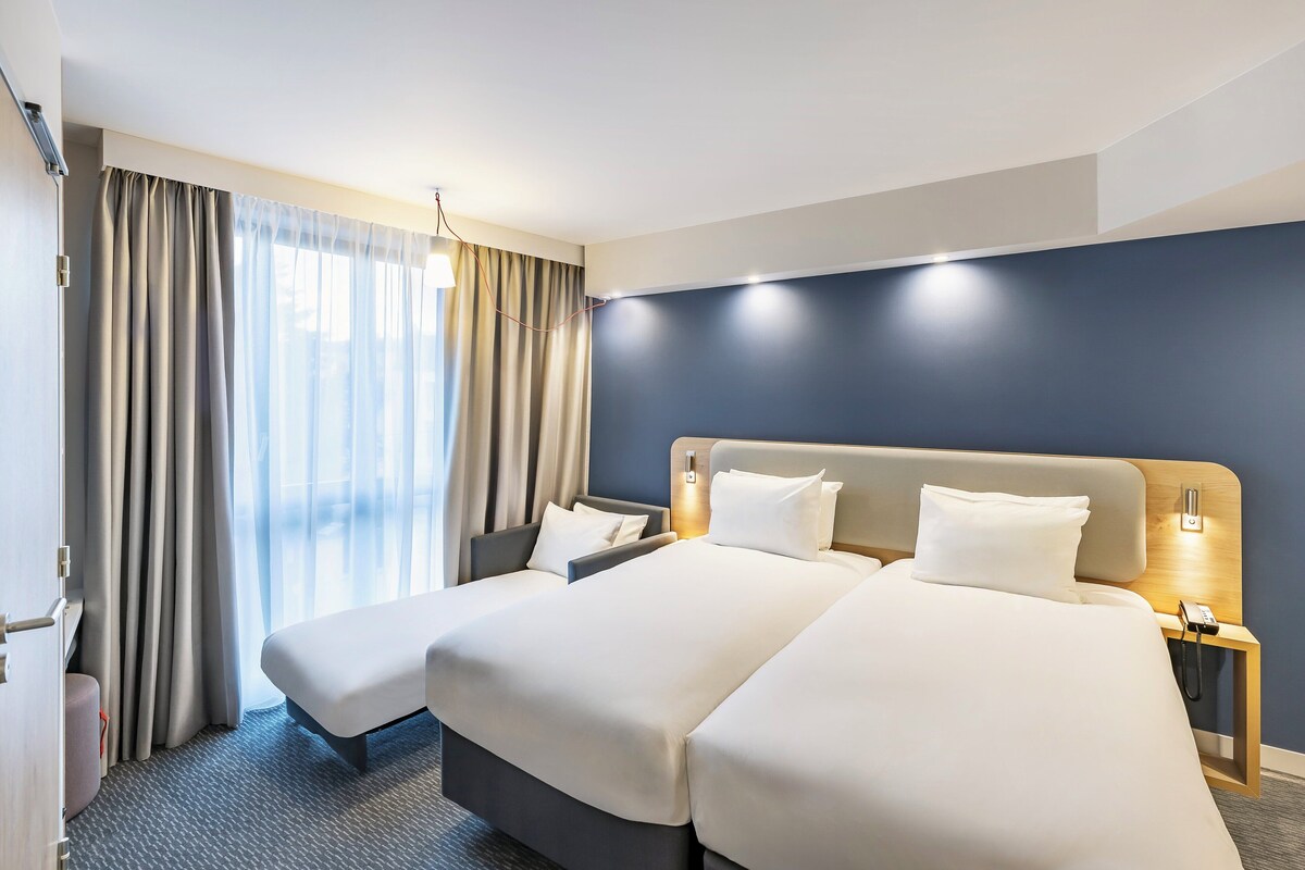 A hotel room with two beds, a desk, and a chair.