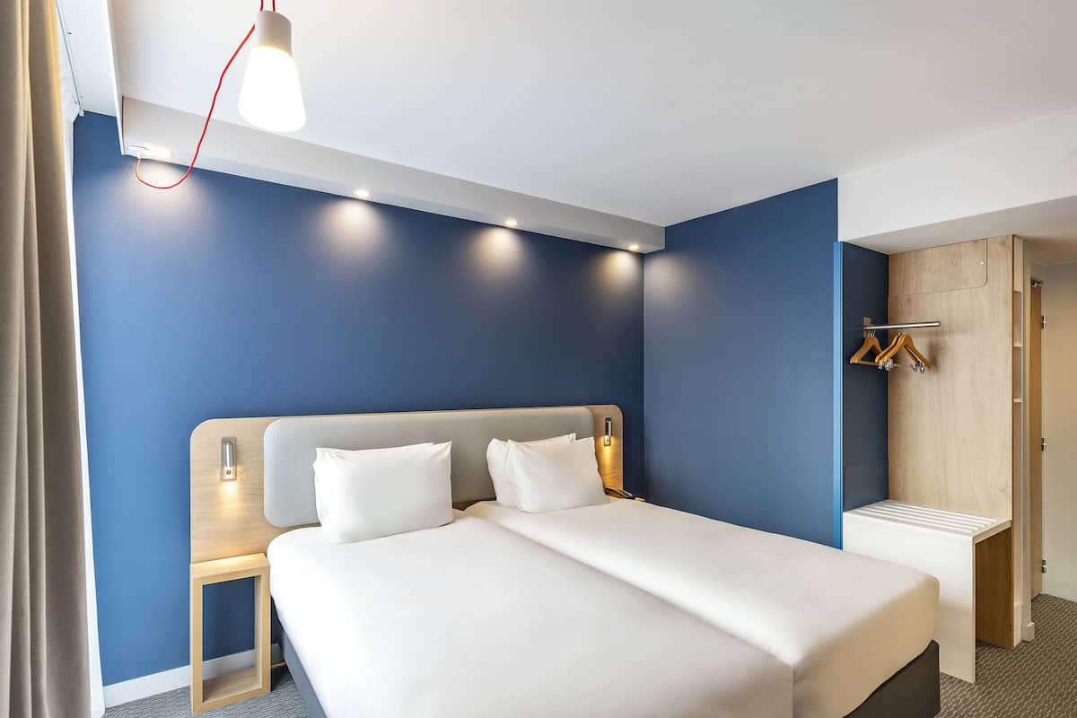 Et moderne hotelværelse med en stor seng, sengeborde, et klædeskab og en bøjlestang.