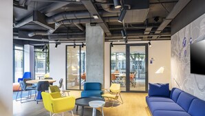 A modern office space with a central seating area, a large sofa, and a dining table. - Holiday Inn Express Paris Poissy by IHG (Poissy)