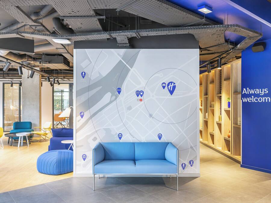 Un interior moderno con un sofá azul, una pared con un mapa y un cartel que dice 'Siempre bienvenidos...'.