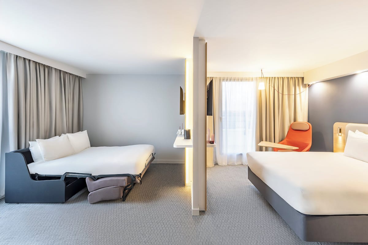 Et hotelværelse med to senge, et skrivebord og en stol.