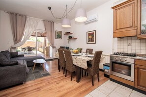 A dining area with a table set for four, surrounded by wicker chairs, a sofa, and a small side table. - Villa Above by Istrabook (Medulin)