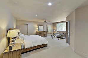 Une chambre à coucher comprenant un lit, une table de chevet, une lampe, une commode, un miroir et un coin salon avec un canapé et une table basse.