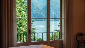 Ein Hotelzimmer mit großem Fenster und Blick auf einen See und Berge.