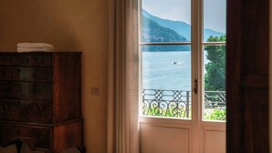 Ein Zimmer mit Blick auf einen See und Berge durch ein Fenster.