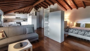 A loft-style room with a kitchen, a sofa, a bed, and built-in shelving. - Loft Venere - MyHomeinComo (Como)