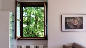 Habitació amb finestra, radiador i una obra d'art enquadrada a la paret.