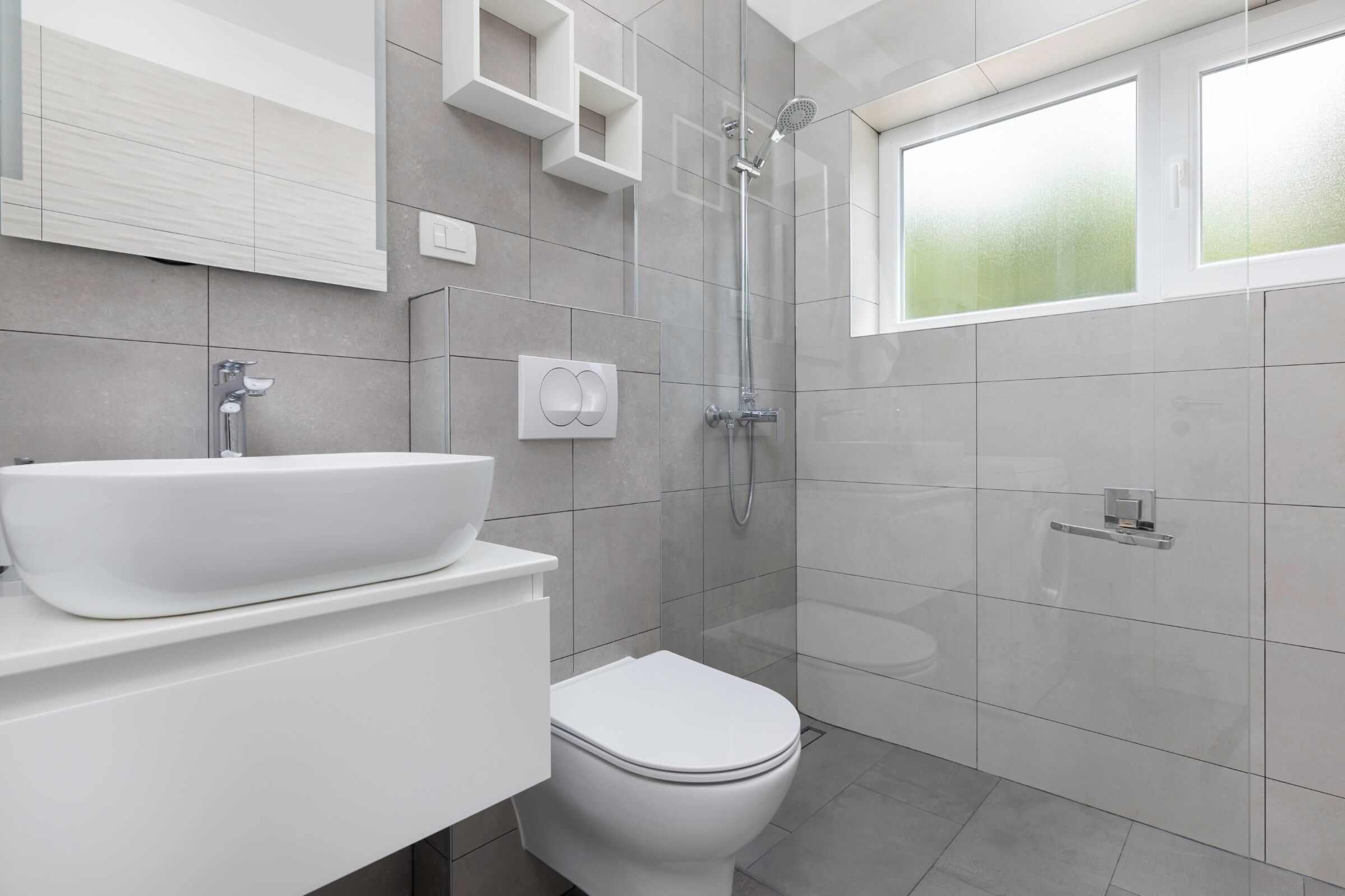 Une salle de bain moderne avec un lavabo, des toilettes et une douche, le tout de couleur blanche.