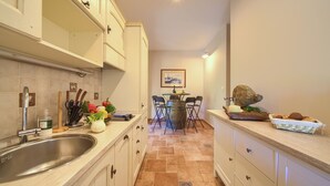 Una cocina con un lavamanos, armarios y una zona de comedor con sillas y una mesa.