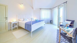 Un dormitorio con cama, mesita de noche, lámpara y una silla.