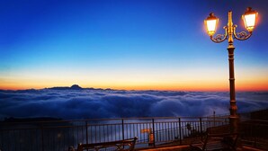 Un banco y un farol con vistas a un mar de nubes.