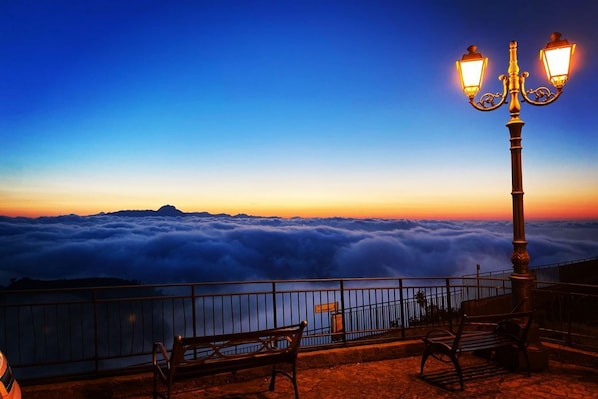A bench and a lamp post overlooking a sea of clouds.