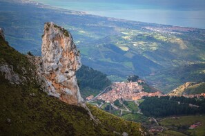 A mountainous landscape with a prominent rocky outcrop and a view of a town below.