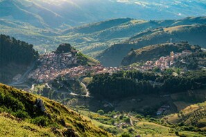 A mountainous town with a prominent church on a hill, surrounded by lush greenery and winding roads.