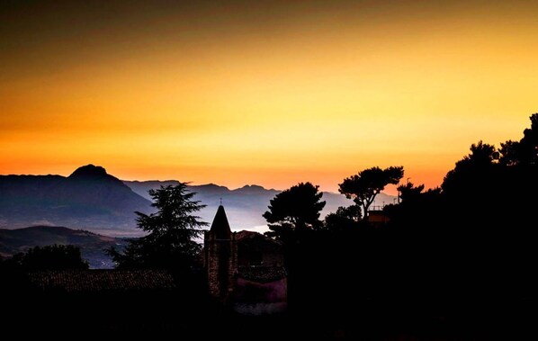 Silueta de una cordillera al atardecer con una iglesia en primer plano.