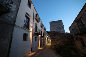 A narrow cobblestone street flanked by historic buildings with balconies and arched windows.