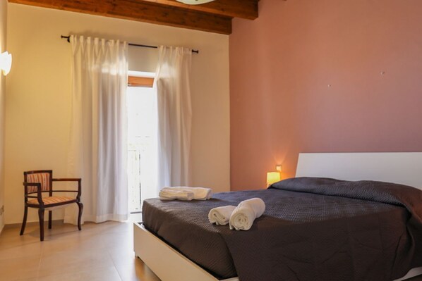 A bedroom with a bed, a chair, and a window with curtains.