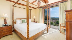 A four-poster bed with a wooden frame, a bedside table with a lamp, and a view of the ocean through a sliding glass door. - End of year specials! - BT701 Beautiful 3 Bed, 3 Bath (Kapolei)
