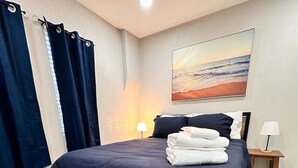 A neatly arranged bedroom with a bed, a bench, a painting, and a nightstand. - Casa Memphis Updated Modern Home (El Paso)
