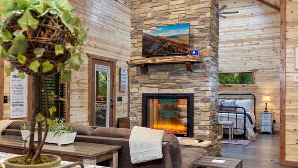 A cozy interior with a stone fireplace, a comfortable seating area, and a television mounted above it.