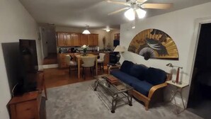Un salon avec un canapé bleu, une table basse en bois et un ventilateur de plafond.